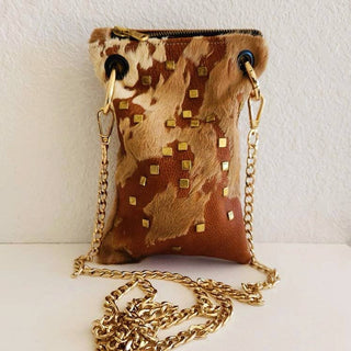 Embellished Hair-on Mini Crossbody Bag - Holt x Palm -  Expertly crafted with shades of mocha and cream, this mini crossbody bag features brass embellishments. It's adorned with a large outside pocket and a small inside pocket with a velvet-lined interior. The heavy-duty Italian zipper ensures durability, while the high-end gold chain strap with swivel hardware adds a touch of sophistication. Dimensions approximately 9"H x 5.5W