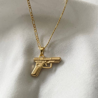 Bang Bang 24k Gold Gun Chain Necklace - Holt x Palm -  Get ready to turn heads with the Bang Bang 24k Gold Gun Chain Necklace. This super cool accessory is gold filled, giving it a stunning shine that will keep you looking fly. Channel your inner boss and keep it G with this one-of-a-kind piece. 17.5” Figaro chain