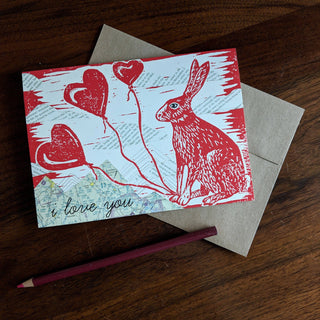 Greeting card | i love you bunny - Holt x Palm -  i love you bunny Show some bunny you love them with this card. Reproduced from an original mixed-media block print by ilikesara / Sara Schalliol-Hodge, which features collaged map mountains, text clouds, and linocut printing. Card measures 4.25" x 5.5" when folded. Printed on 100 lb cream cover paper. Kraft envelope included. Blank interior. Packaged in a clear cellophane sleeve. Designed and printed in Denver, Colorado.