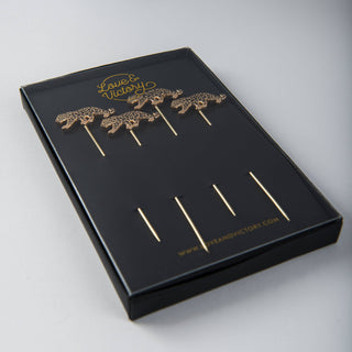 Leopard Cocktail Picks - Holt x Palm -  Leopard swizzlers to gussy up your drinks. An alluring set 4 of cocktail picks adorned with elegantly leaping leopards. Gold picks with black enamel finish, packaged in our custom printed box. Approximate dimensions: 4” long pick with 0.5 x 1.25” leopard. Hand Wash