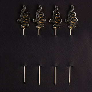 Snake Cocktail Picks - Holt x Palm -  Serpentine swizzlers to gussy up your drinks. An alluring set of 4 cocktail picks adorned with elegantly coiled snakes, ready to tempt you with another beverage. Gold picks with black enamel finish, packaged in our custom printed box. Approximate dimensions: 4” long pick with 1.25 x 0.625” snake. Hand Wash