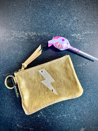 The Cutest Up-Cycled Leather Lightening Bolt Pouch You Ever Did See.... - Holt x Palm -  We love these little pouches!! They just keep your purse organized in style. Use them for Airpods, cash, ID, pills, whathaveyou! It's your little good time pouch...attach it to your purse or just your belt buckly and go out and have you a good 'ol time! Buy a few for friends...they will adore them! DETAILS: Measures 5"x3.5". Unlined. Brass zipper and key ring Appliques are hand cut and attached with mini rivets.