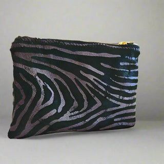 Emerald Zebra Bolt Pouch - Holt x Palm -  This Bolt Pouch is made from high-quality Italian leather with a hair-on pewter zebra effect. It features a stylish gold bolt accent. It is lined with plush rust velvet and has a heavy-duty Italian zipper for added durability. The pouch also includes a small interior pocket for extra organization. Approximate dimensions: 7.75" W x 6" H. Handcrafted in the USA