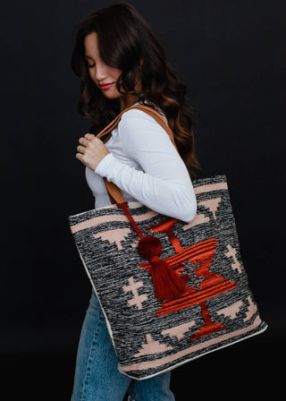 Faded Black, Tan & Red Aztec Tote - Holt x Palm -  Go bold and bohemian with our Faded Black, Tan & Red Aztec Tote! This extra large tote is perfect for carrying all your essentials in style. Embrace your free-spirited side with the timeless Aztec design. It's a tote, it's a statement piece - it's everything you need. Aztec-chic never looked so good! Description: Faded black, tan, red & rust Aztec tote w/ Red pom tassel detail 17" x 6.5" x 14.5" 100% Cotton Min.