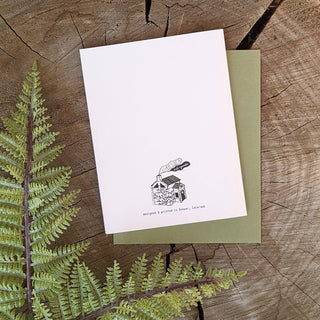 Greeting card | skull planter - Holt x Palm -  skull planter An archival print of various fern specimens, housed in a skull vase with tiki vibes. Reproduced from original illustrations by ilikesara / Sara Schalliol-Hodge. -Card measures 4.25" x 5.5" when folded -Printed on 100 lb off-white cover paper -Avocado green envelope included -Blank interior -Packaged in a clear cellophane sleeve Designed and printed in Denver, Colorado.