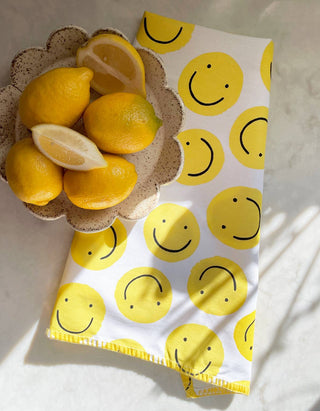 Smiley Tea Towel - Holt x Palm -  Our vibrant tea towels are just the thing to add a touch of colorful flair to your kitchen, or a thoughtful hostess/housewarming gift! Woven from 100% absorbent cotton and printed with our charming, hand-painted designs, each towel is embellished with contrasting embroidery along the seaming. • 21″ X 28″ • HANGING LOOP • EMBROIDERED TRIM