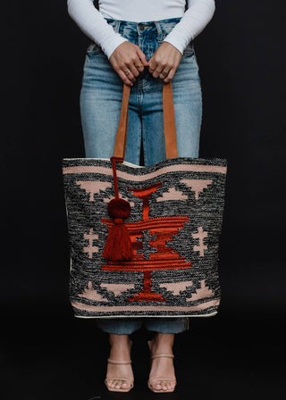 Faded Black, Tan & Red Aztec Tote - Holt x Palm -  Go bold and bohemian with our Faded Black, Tan & Red Aztec Tote! This extra large tote is perfect for carrying all your essentials in style. Embrace your free-spirited side with the timeless Aztec design. It's a tote, it's a statement piece - it's everything you need. Aztec-chic never looked so good! Description: Faded black, tan, red & rust Aztec tote w/ Red pom tassel detail 17" x 6.5" x 14.5" 100% Cotton Min.