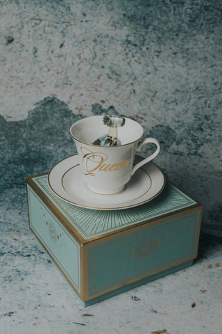 The Queens Tea Cup w/ Gift Box - Holt x Palm -  Regale yourself in the luxury of our newest collection of fine Bone China from Spitfire Girl. Do you want to treat her like the Queen she is? Or treat yourself because you are a Queen that only deserves the best. All Teacups come with a cup and saucer and are packaged in an elegant blue gift box with 24K gold accents. Plated 24k gold material from Germany Dishwasher safe Cup measures 6" Cup 3.5" w 3.10 h