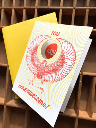 You Radiate Pure Awesome Card - Holt x Palm -  "Spread smiles and pure awesome vibes with this playful greeting card. Perfect for showing your rad friends and loved ones how much they mean to you. Get ready to make someone's day!" • blank inside and measures 4.25”x5.5” folded • folded card is letterpress printed in warm red and yellow ink on 100% cotton paper • with circle die cut on front • accompanied by an A2 yellow envelope