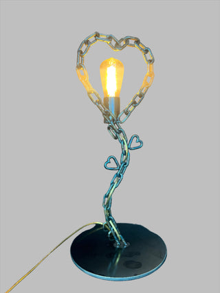 The Heart Lamp - Holt x Palm -  Brighten up any room with The Heart Lamp! This custom-made, one-of-a-kind lamp features a unique "chain heart" design and measures 22" x 10". A perfect addition to any space, it's sure to be a conversation starter. (Heart emoji)